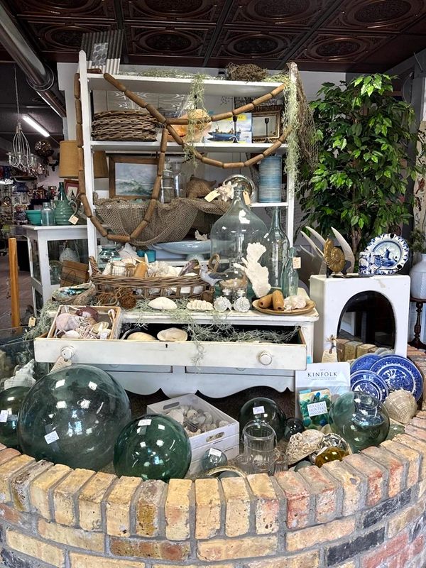 Seashells, glass fishing floats and coastal decor displayed on white shelves