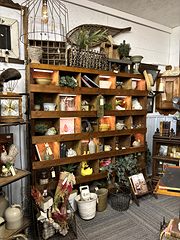 Tall wooden cubby shelf filled with pottery, books, baskets and farmhouse decor