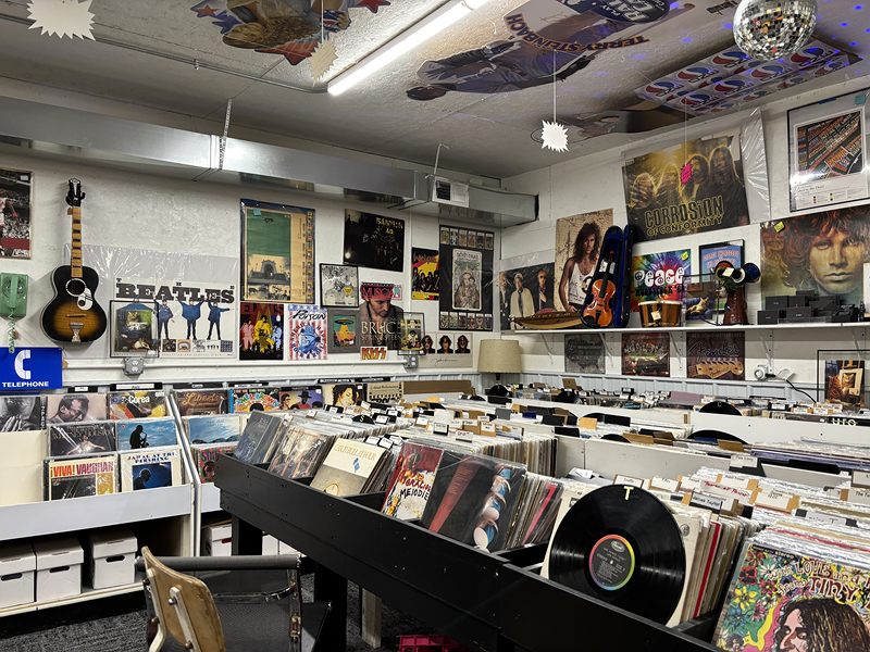Record room with rows of vinyl albums, a Beatles poster and a guitar on the wall