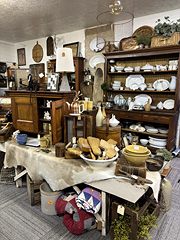 Rustic furniture with a hutch of white dishes, a hide-covered table, baskets and pottery