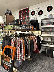 Racks of flannel shirts and leather jackets with a Harley-Davidson sign and records on the wall