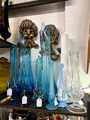 Blue and clear glass swung vases below a pair of lion-head wall plaques