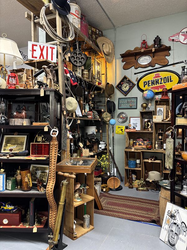 Corner packed with vintage signs, including Pennzoil and an exit sign, plus lanterns and tools