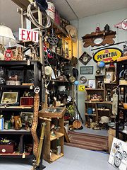 Corner packed with vintage signs, including Pennzoil and an exit sign, plus lanterns and tools