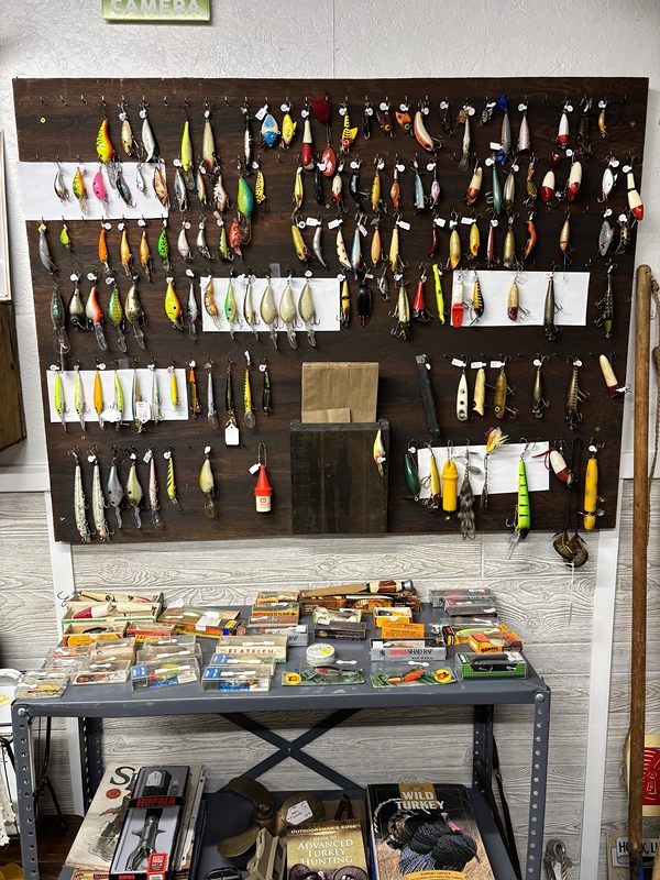 Pegboard wall of vintage fishing lures above a table of tackle