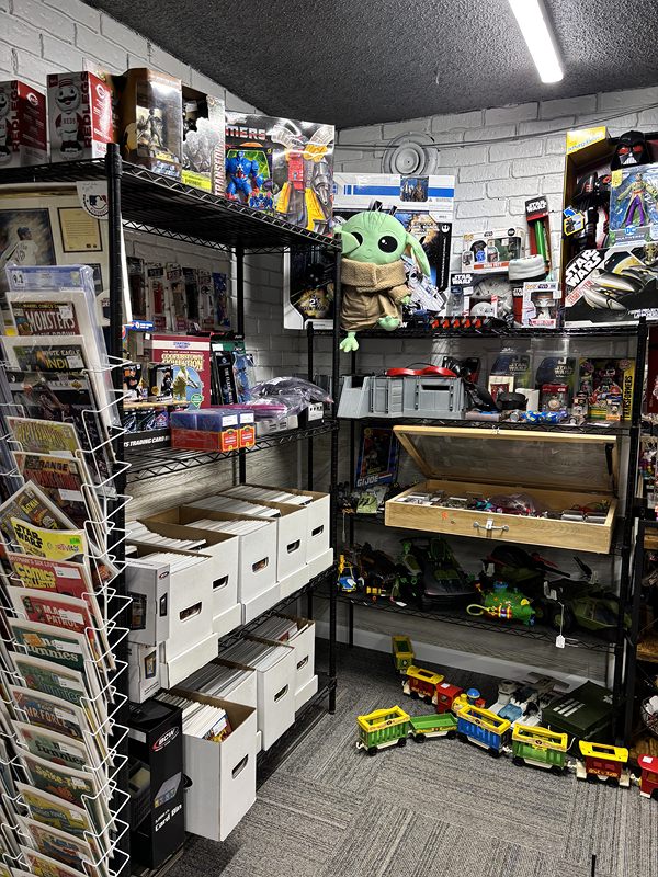 Shelves of boxed toys and collectibles beside a spinner rack of comic books