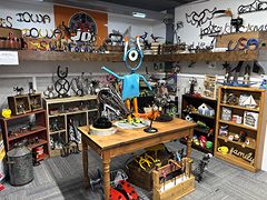 Scrap-metal yard art, including a blue robot figure on a wooden table, surrounded by metal sculptures
