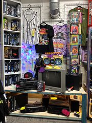 Booth of band T-shirts, action figures and electronics under colorful lights
