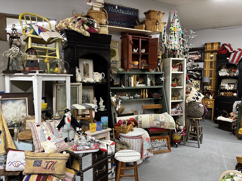 Country decor booth with hutches, quilts, lamps and a small Christmas tree
