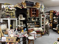 Country decor booth with hutches, quilts, lamps and a small Christmas tree
