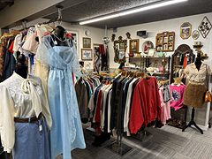 Vintage clothing with a light blue dress on a mannequin and racks of jackets and shirts