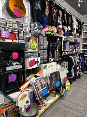Aisle of CDs, DVDs and band shirts with bright sale tags and a guitar on the wall