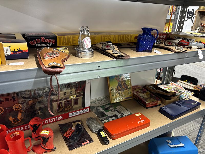 Shelf of Western collectibles, including a leather holster, cap guns and a pocket watch