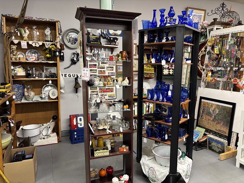 Wooden shelves and a tall case of cobalt blue glass, white enamelware and collectibles