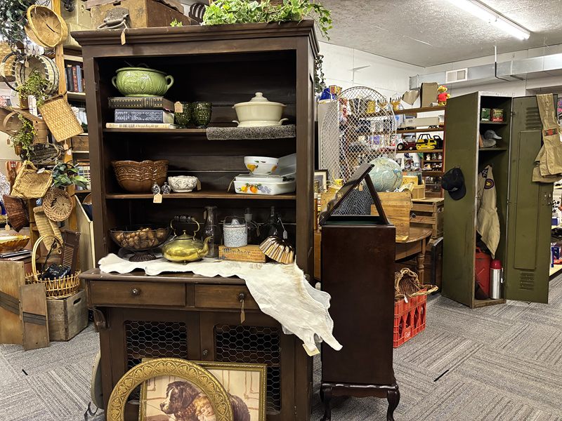 Dark wood hutch with green pottery and baskets next to an olive green metal locker