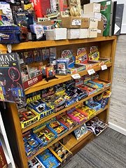 Wooden shelves of boxed vintage toys, including Batman and Alien figures