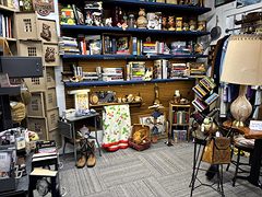 Blue shelves stacked with books and collectibles, with a lamp, a quilt and cowboy boots