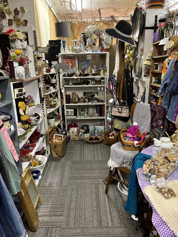 Narrow aisle of shelves with dolls, hats and collectibles