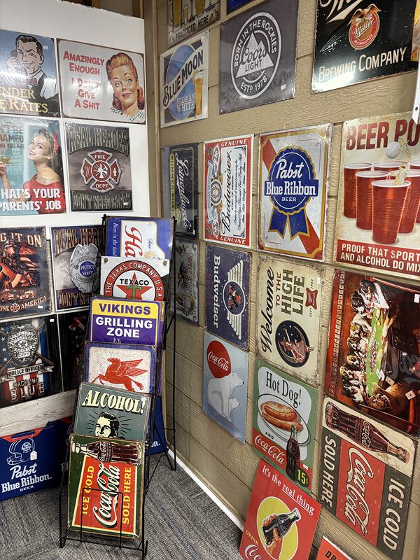 Wall of vintage metal beer and soda signs, including Pabst Blue Ribbon and Coca-Cola