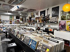 Long bins of vinyl records with music posters and memorabilia on the walls
