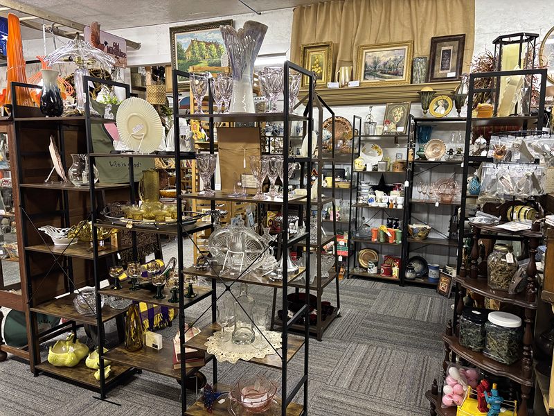 Dark metal shelves of glassware, hats and home decor in a room full of booths
