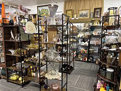 Dark metal shelves of glassware, hats and home decor in a room full of booths
